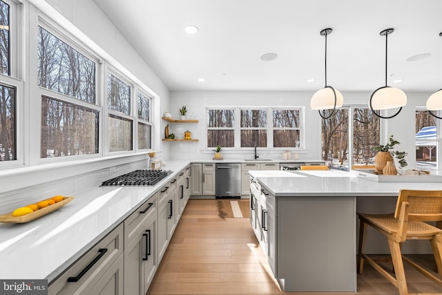 kitchen featuring a kitchen bar, appliances with stainless steel finishes, gray cabinetry, sink, and decorative light fixtures