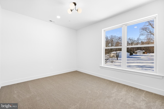 spare room featuring carpet flooring and a notable chandelier