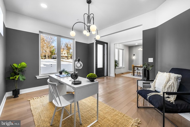 home office with light hardwood / wood-style floors and an inviting chandelier