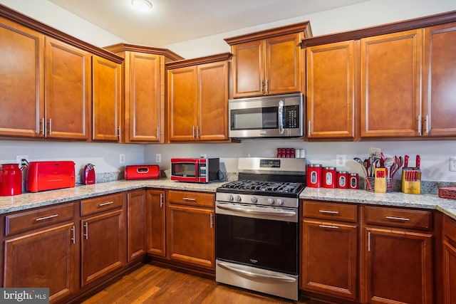 kitchen with light stone counters, dark hardwood / wood-style flooring, and stainless steel appliances