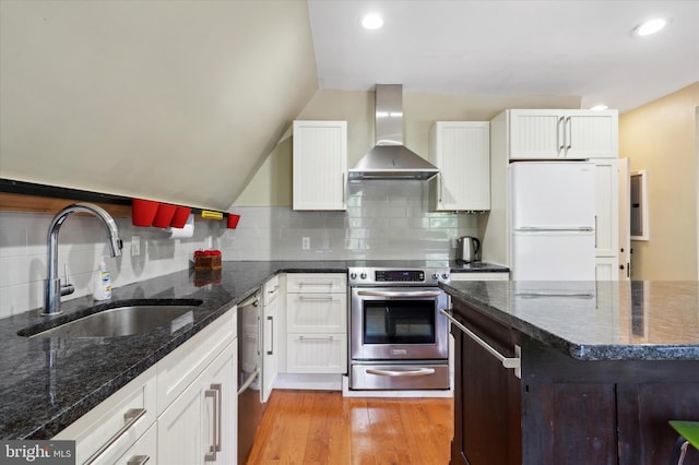 kitchen with decorative backsplash, stove, wall chimney exhaust hood, white cabinets, and white fridge