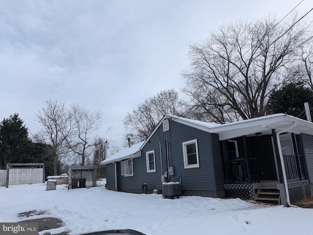 view of snowy exterior with covered porch and central air condition unit