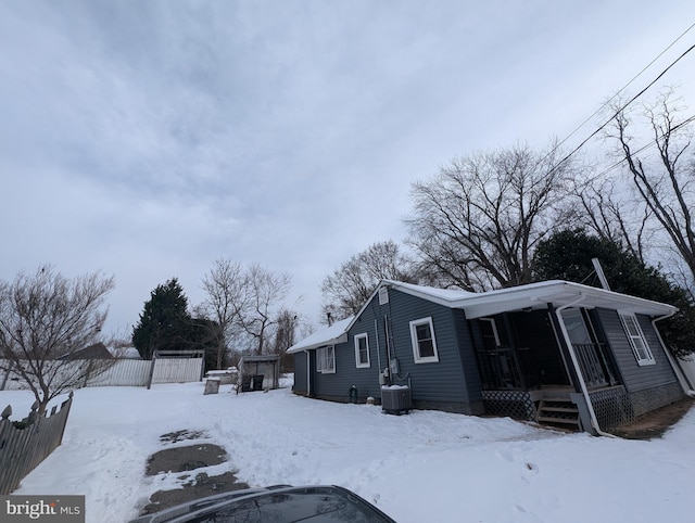 snow covered property featuring covered porch and cooling unit