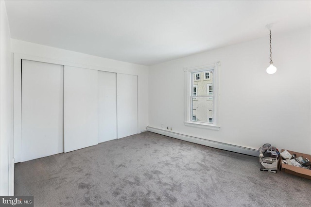 unfurnished bedroom with carpet, a baseboard radiator, and a closet