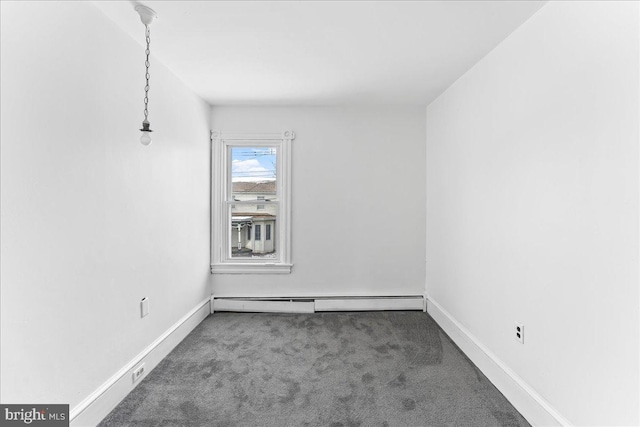 empty room with dark carpet and a baseboard heating unit