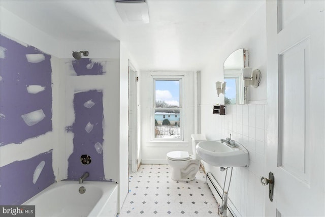 full bathroom with sink, a baseboard heating unit, toilet, shower / washtub combination, and tile walls