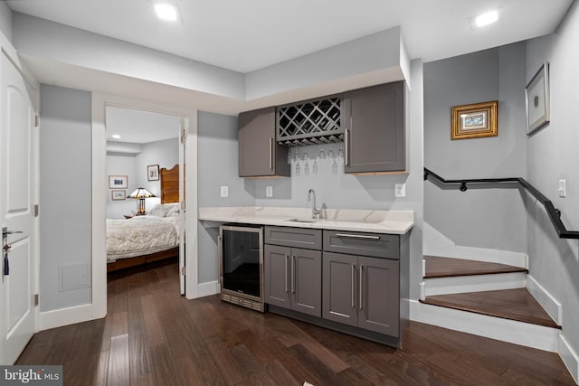 bar with dark hardwood / wood-style flooring, wine cooler, gray cabinetry, and sink