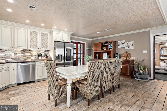 dining area featuring a textured ceiling, crown molding, and french doors