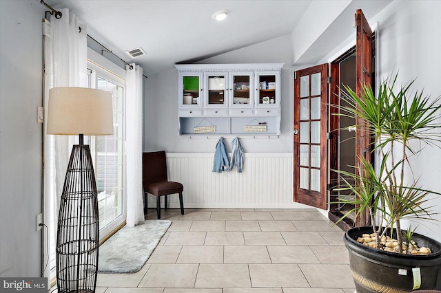 mudroom with light tile patterned floors and vaulted ceiling