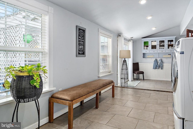 interior space featuring light tile patterned floors, lofted ceiling, and stacked washer / dryer