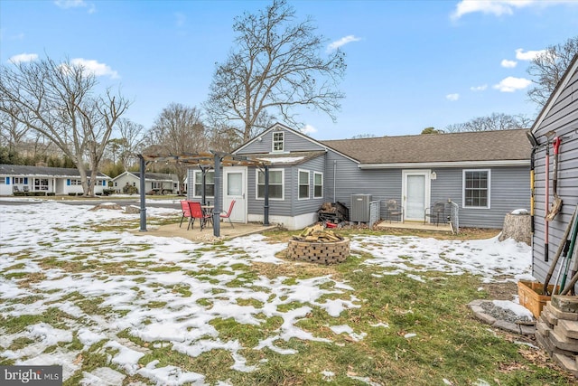 snow covered house with central air condition unit, an outdoor fire pit, a patio, and a pergola