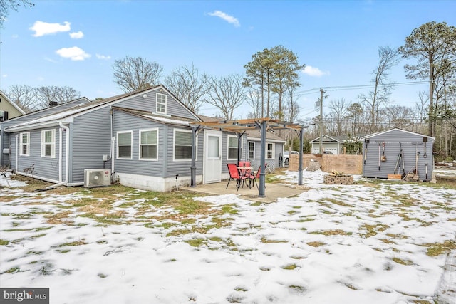 snow covered property with ac unit, a storage shed, a patio, and a pergola