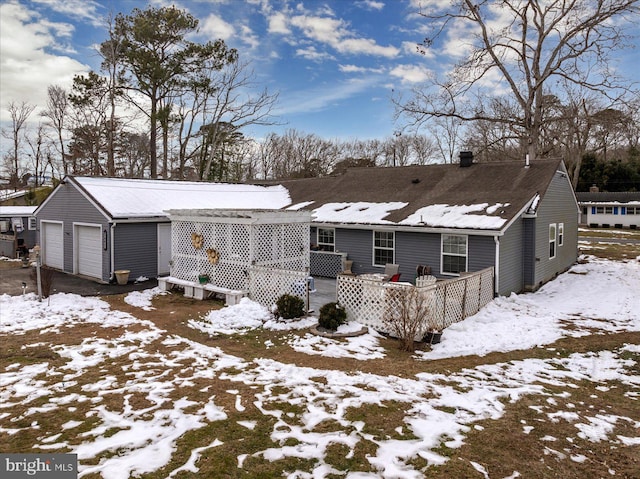 snow covered house featuring a garage