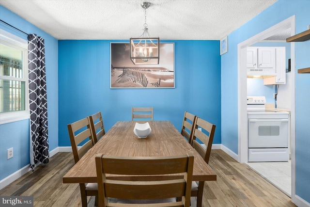 dining area featuring hardwood / wood-style flooring, a textured ceiling, and an inviting chandelier