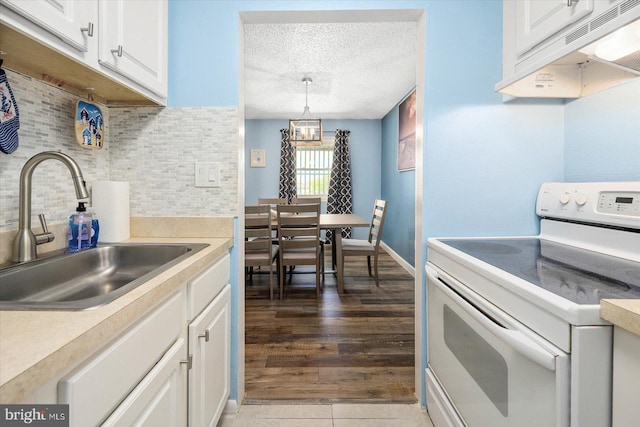 kitchen with decorative backsplash, white electric range oven, sink, pendant lighting, and white cabinets