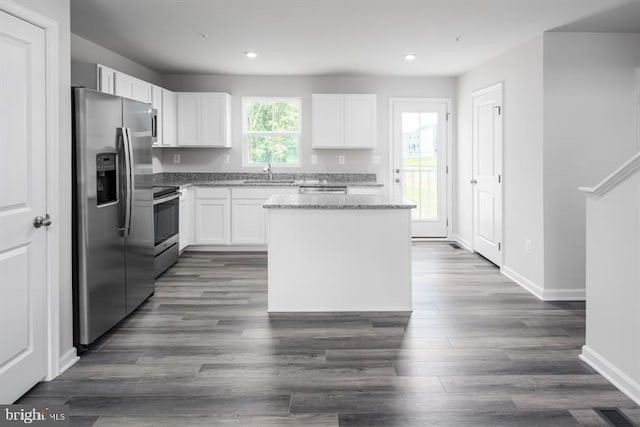 kitchen with a center island, dark hardwood / wood-style floors, light stone countertops, white cabinetry, and stainless steel appliances