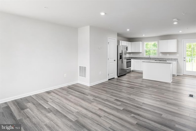 kitchen featuring light wood-type flooring, stainless steel fridge with ice dispenser, a center island, and white cabinetry