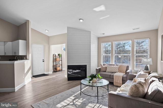 living room with lofted ceiling, a fireplace, and light hardwood / wood-style flooring