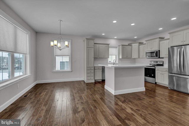 kitchen with gray cabinetry, hanging light fixtures, appliances with stainless steel finishes, and a chandelier