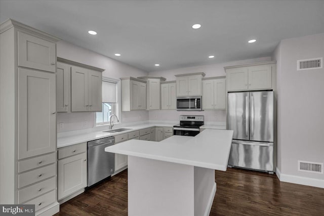 kitchen featuring a center island, stainless steel appliances, dark wood-type flooring, and sink