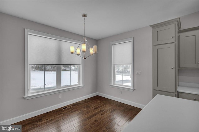 unfurnished dining area featuring dark wood-type flooring and a notable chandelier