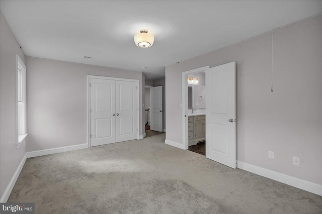 unfurnished bedroom featuring carpet flooring, a closet, and ensuite bath