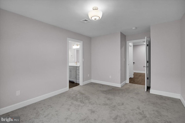 unfurnished bedroom featuring ensuite bathroom and light carpet