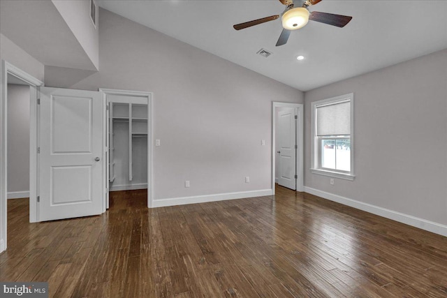 unfurnished bedroom with ceiling fan, dark hardwood / wood-style floors, a spacious closet, and vaulted ceiling