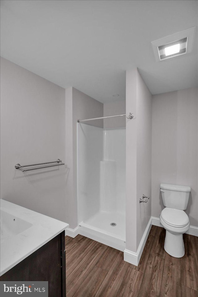 bathroom with hardwood / wood-style floors, vanity, toilet, and walk in shower