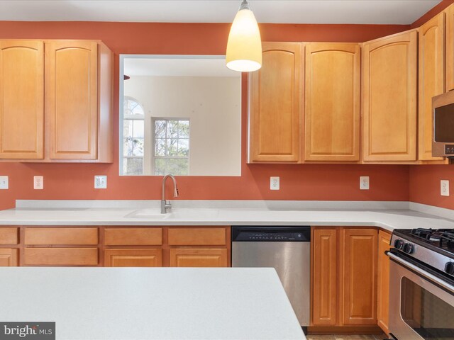 kitchen featuring stainless steel appliances, light brown cabinets, hanging light fixtures, and sink