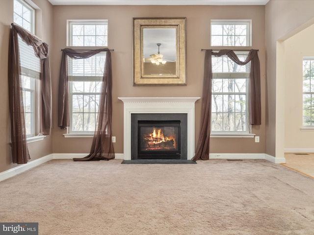 unfurnished living room featuring ceiling fan, carpet, and plenty of natural light