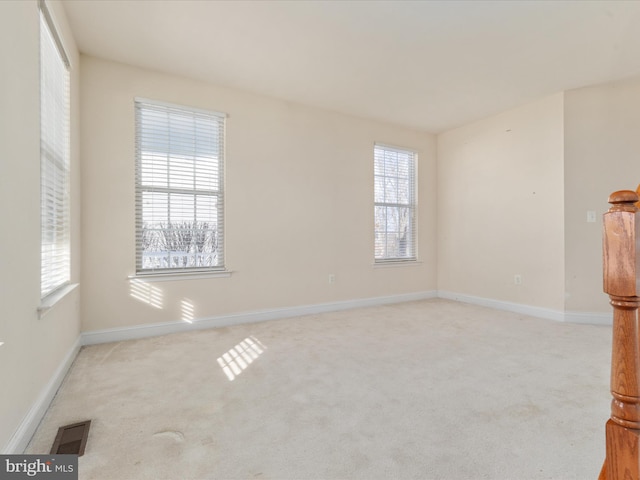 empty room featuring light colored carpet and plenty of natural light