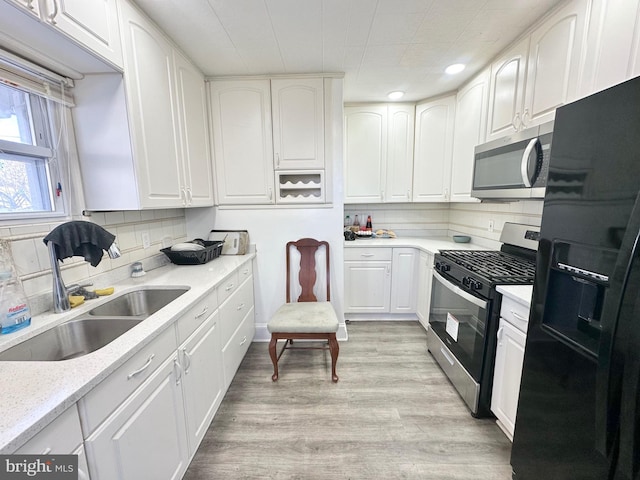 kitchen featuring tasteful backsplash, white cabinetry, sink, and stainless steel appliances