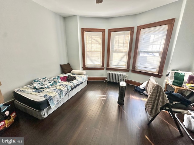 bedroom with radiator heating unit and dark hardwood / wood-style floors