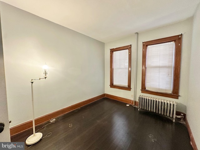 spare room with radiator heating unit and dark wood-type flooring