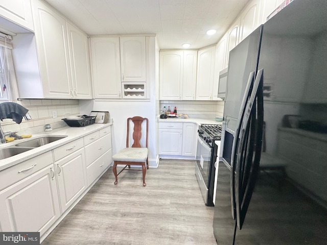 kitchen with refrigerator with ice dispenser, decorative backsplash, white cabinetry, and stainless steel gas range