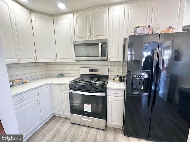 kitchen with white cabinets, backsplash, appliances with stainless steel finishes, and light hardwood / wood-style flooring