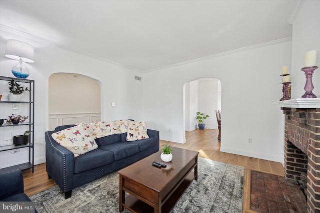 living room featuring wood-type flooring, crown molding, and a fireplace