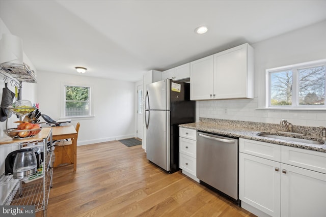 kitchen with sink, white cabinetry, stainless steel appliances, light stone counters, and tasteful backsplash