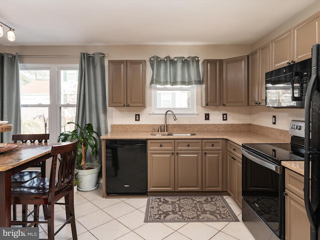 kitchen with sink, light tile patterned floors, black appliances, light stone countertops, and decorative backsplash