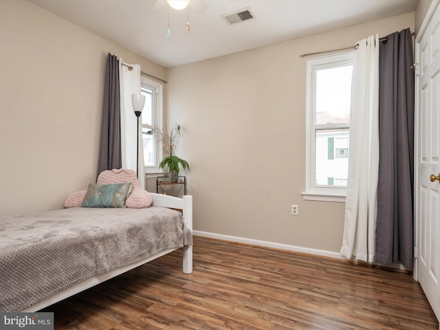 bedroom with hardwood / wood-style flooring, ceiling fan, and multiple windows