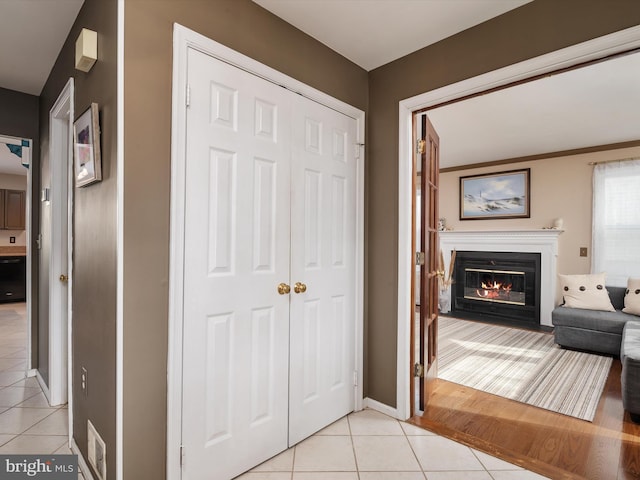 corridor featuring ornamental molding and light tile patterned flooring