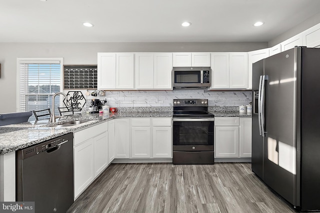 kitchen featuring hardwood / wood-style floors, sink, appliances with stainless steel finishes, white cabinets, and light stone counters