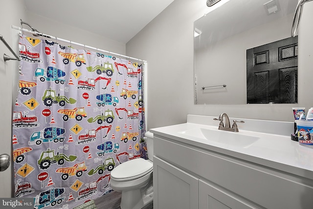 bathroom with toilet, vanity, and walk in shower