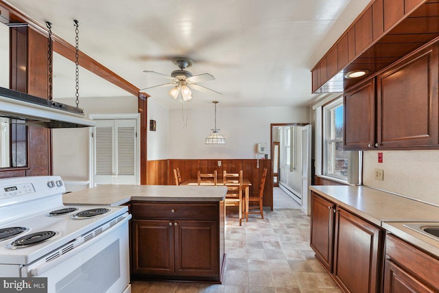 kitchen featuring white range with electric stovetop, wood walls, ceiling fan, and hanging light fixtures