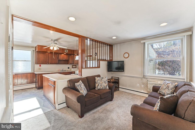 carpeted living room with ceiling fan, sink, and a baseboard radiator