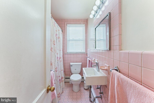 bathroom with a baseboard heating unit, tile patterned floors, sink, toilet, and tile walls