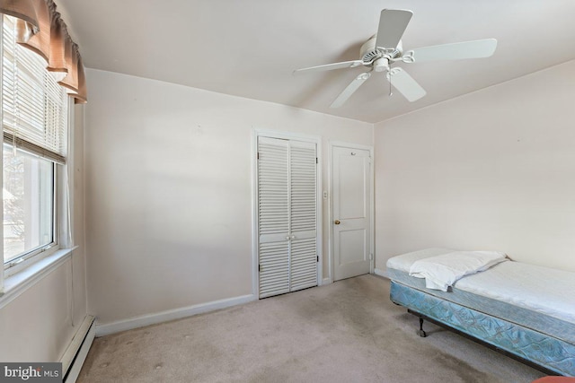 bedroom with multiple windows, ceiling fan, light carpet, and a baseboard heating unit