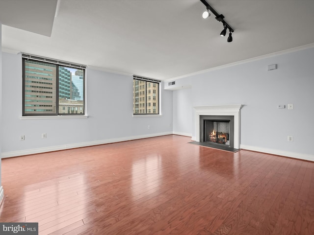 unfurnished living room with track lighting, ornamental molding, and hardwood / wood-style flooring