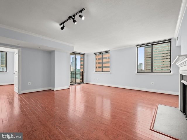 unfurnished living room featuring ornamental molding, track lighting, and wood-type flooring